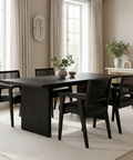 Dining room with a black table and chairs in a bright room with large windows.