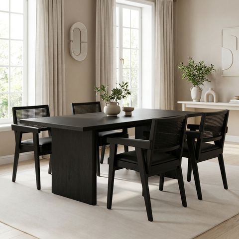 Dining room with a black table and chairs in a bright room with large windows.