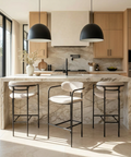 Modern kitchen with marble island, bar stools, and wooden cabinets.