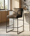 Bar stool with black metal frame and gray cushioned seat in a modern kitchen.