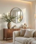 Modern living room with a beige sofa, wooden sideboard, and round mirror.