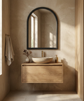 Bathroom with wooden vanity, round mirror, and natural light